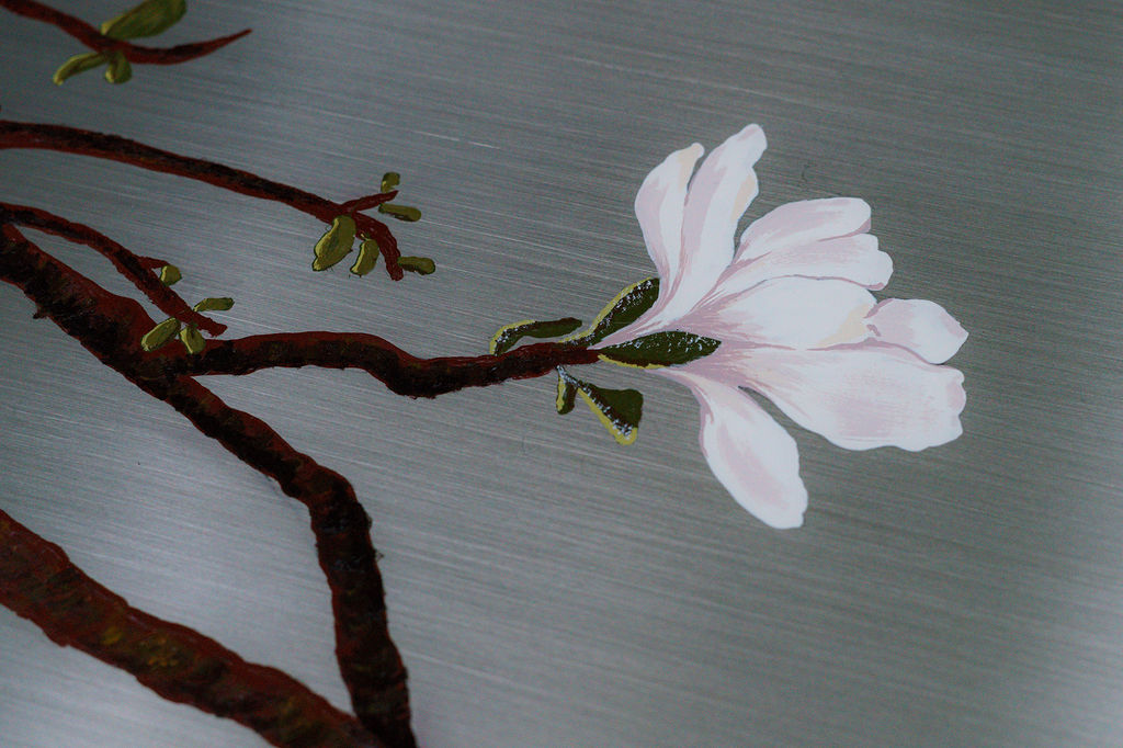 Detalle de las ramas de magnolia sobre el acero cepillado