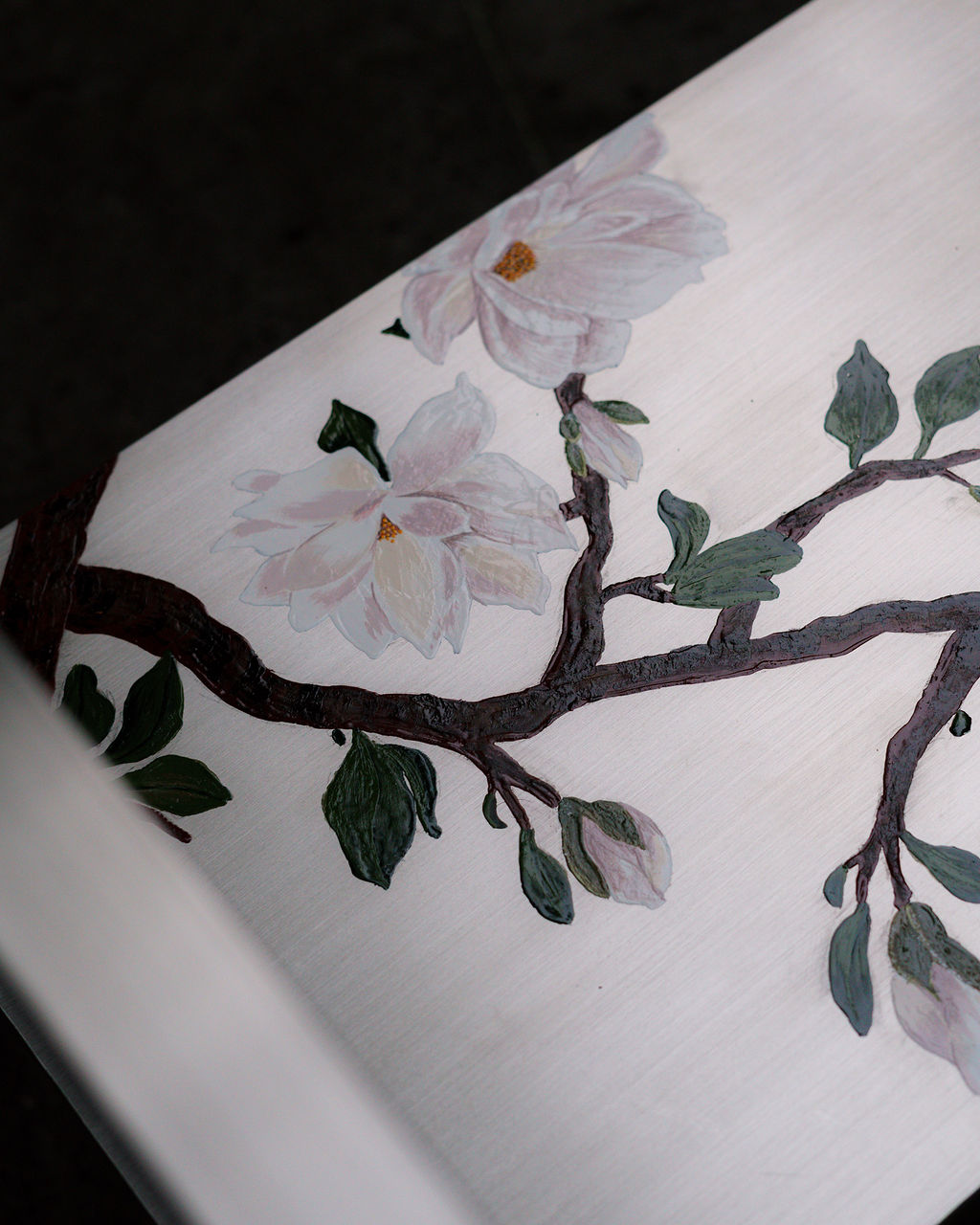 Detalle de las ramas de magnolia sobre el acero cepillado