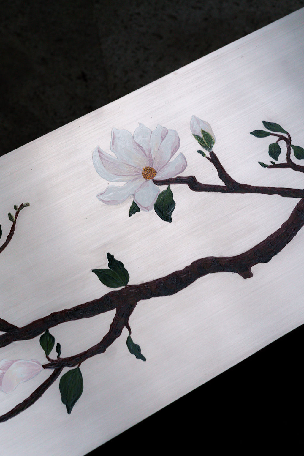 Detalle de las ramas de magnolia sobre el acero cepillado