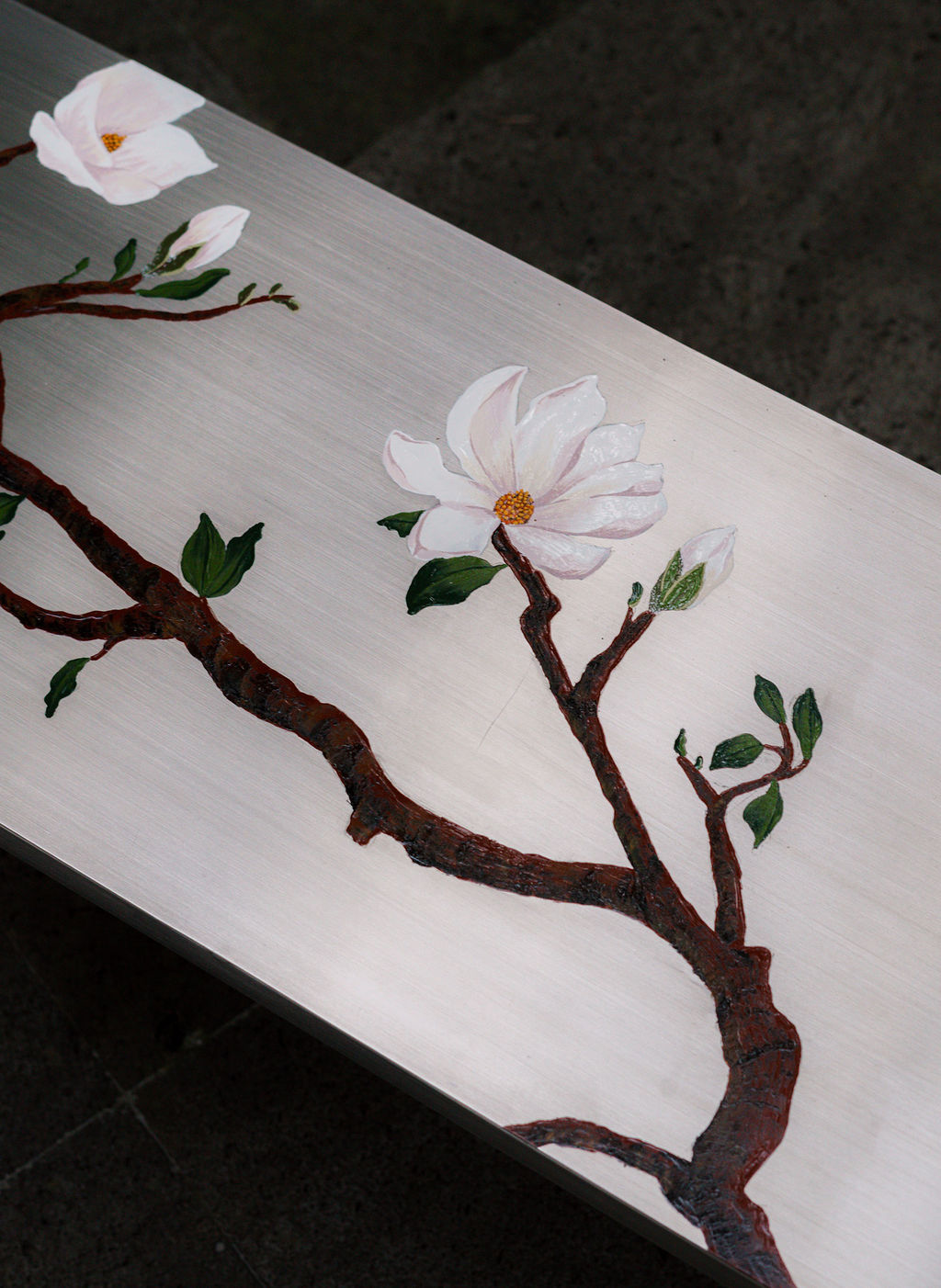 Detalle de las ramas de magnolia sobre el acero cepillado